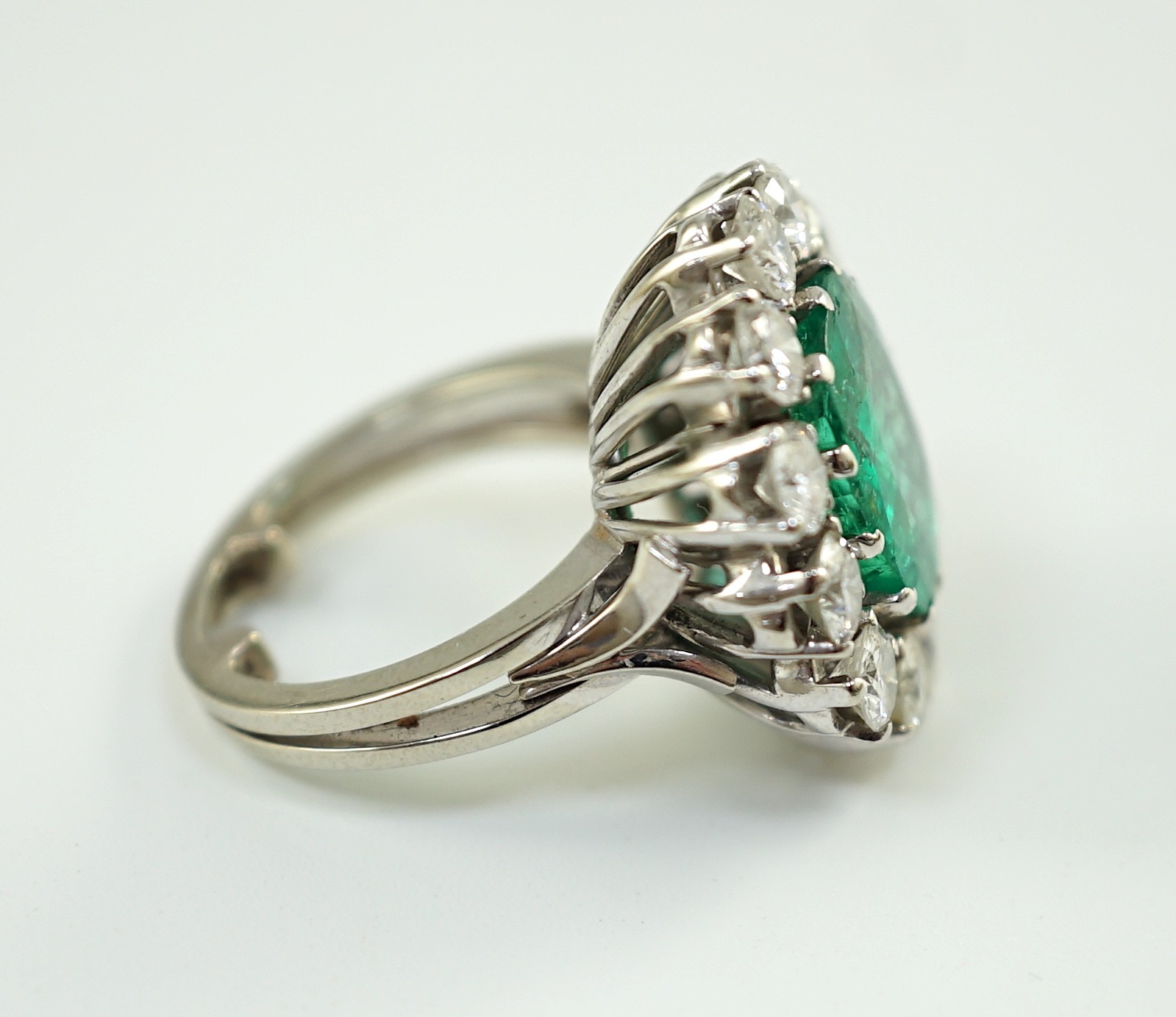 An impressive platinum, emerald and diamond set oval cluster dress ring